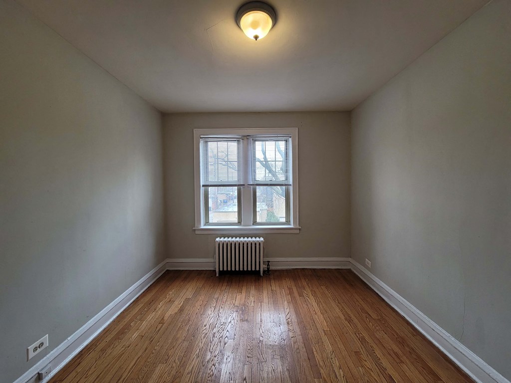 an empty room with wood floors and a window