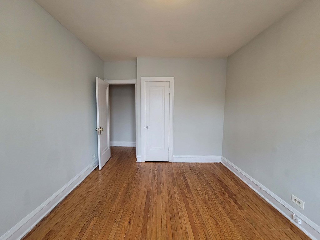 a bedroom with wood flooring and white walls