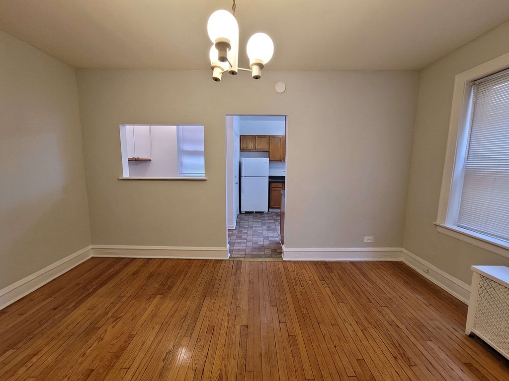 a empty living room with wood floors and a kitchen