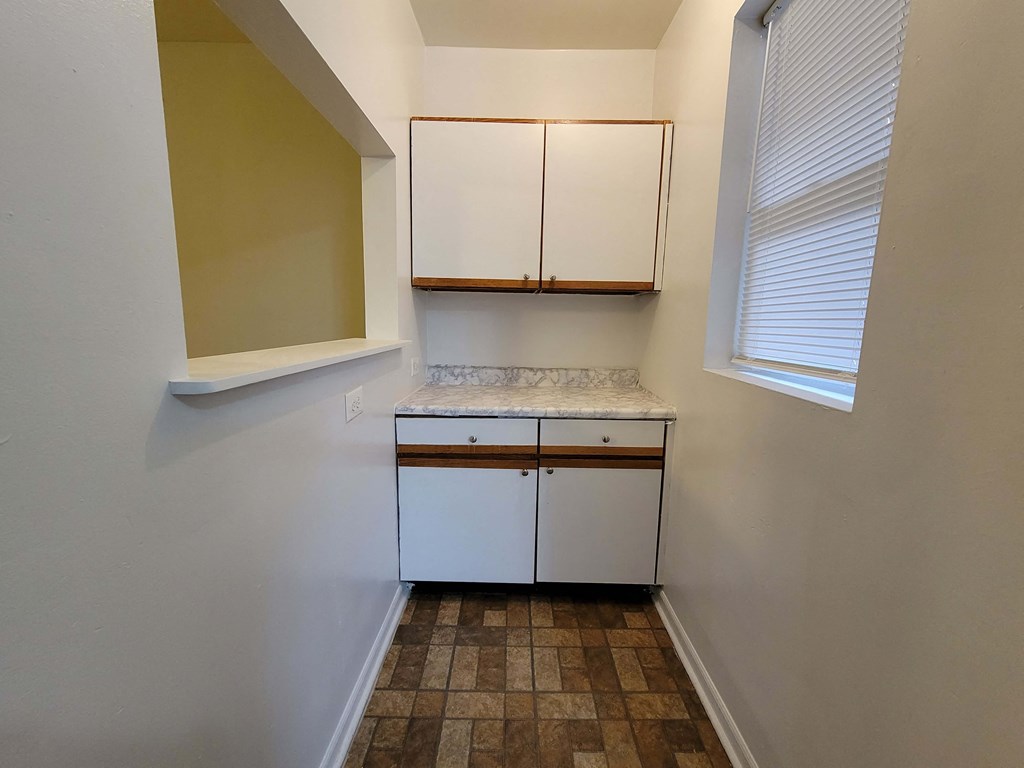 a small kitchen with white cabinets and a window