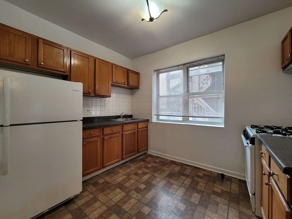 an empty kitchen with a stove refrigerator and a window