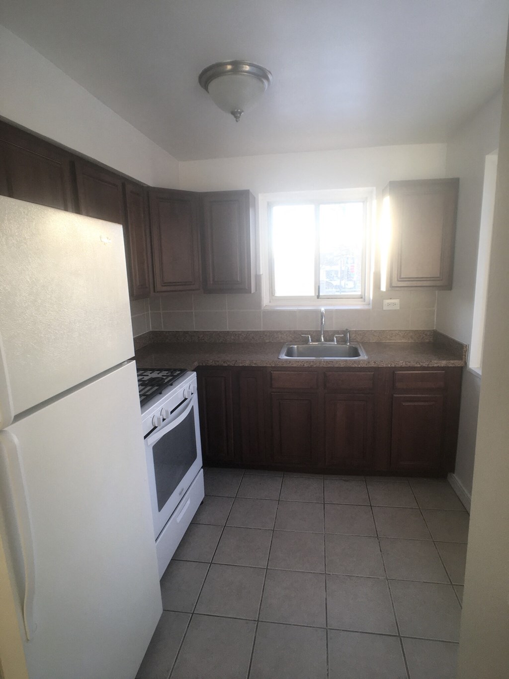 an empty kitchen with white appliances and wooden cabinets