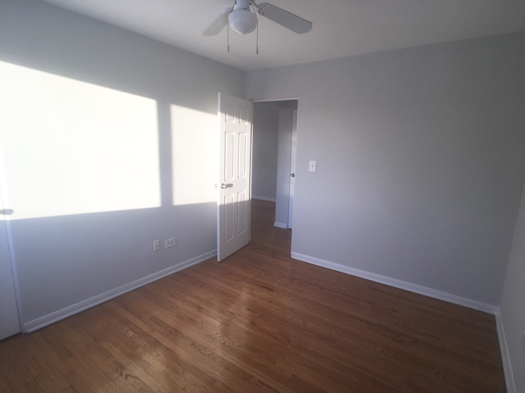 an empty living room with wood floors and a ceiling fan