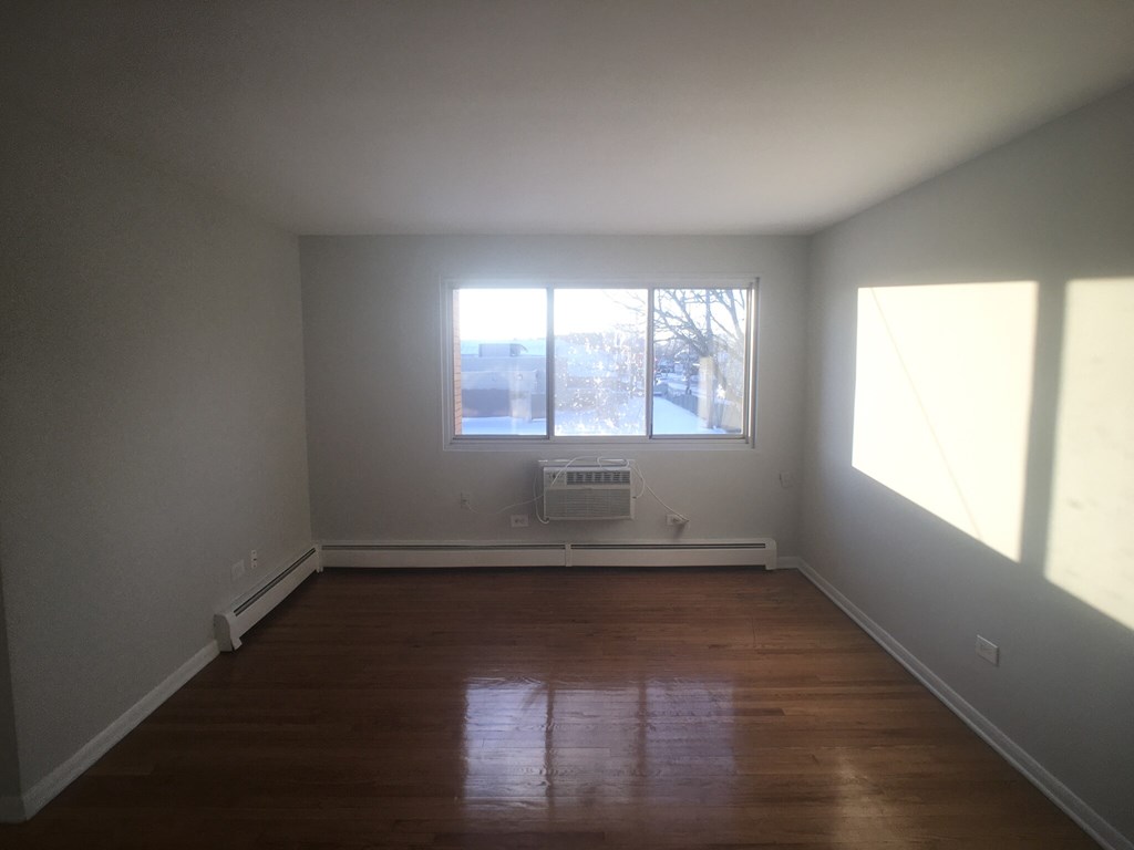 an empty room with a window and wooden floors