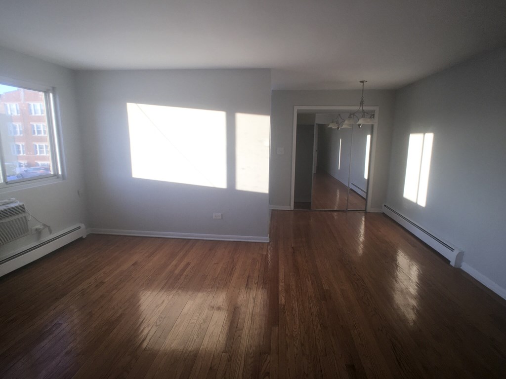 an empty living room with hardwood floors and a large window