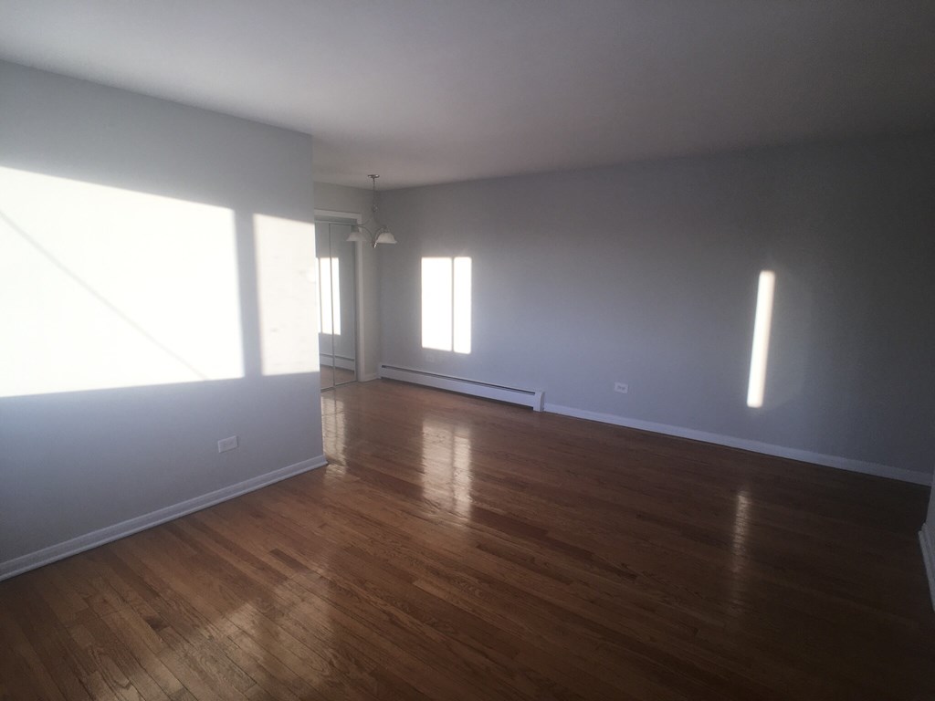 an empty living room with wood floors and grey walls