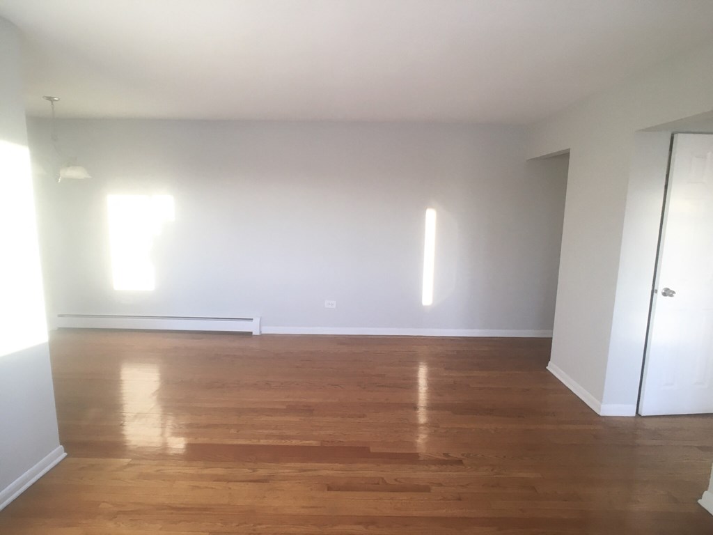 an empty living room with wooden floors and white walls