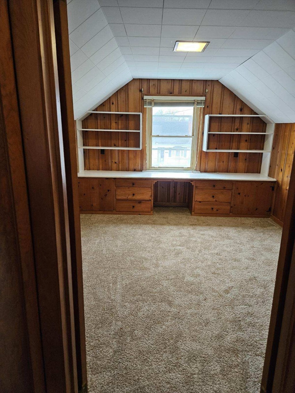 an empty room with wooden shelves and a window