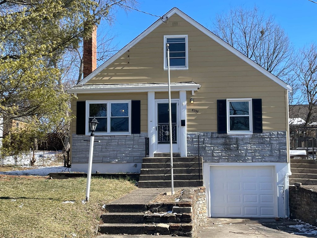 a tan house with a white door and a white garage door