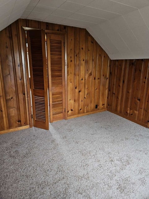 a bedroom with a carpeted floor and wooden walls