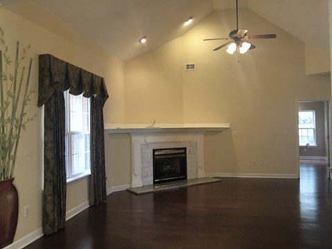 an empty living room with a fireplace and a ceiling fan