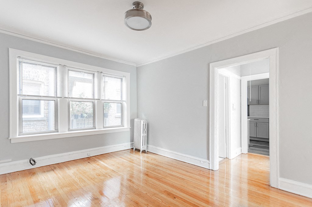 an empty living room with a hard wood floor and white walls