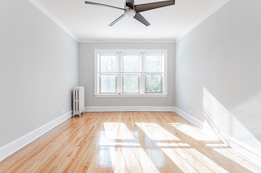an empty room with wooden floors and a ceiling fan