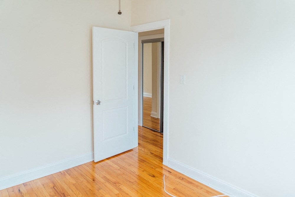 an empty room with a door open to a hallway and a door to a bedroom