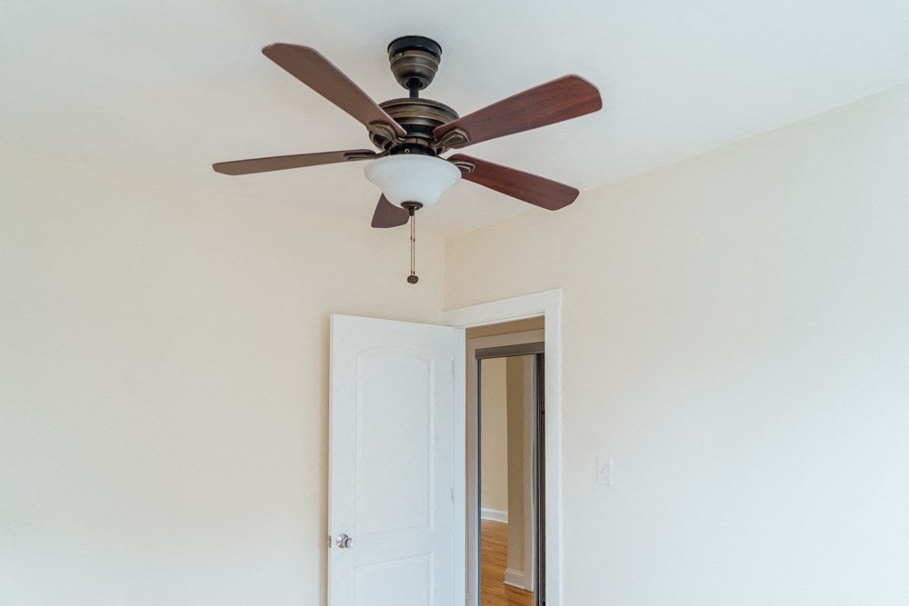 an empty room with a ceiling fan and a door to a hallway