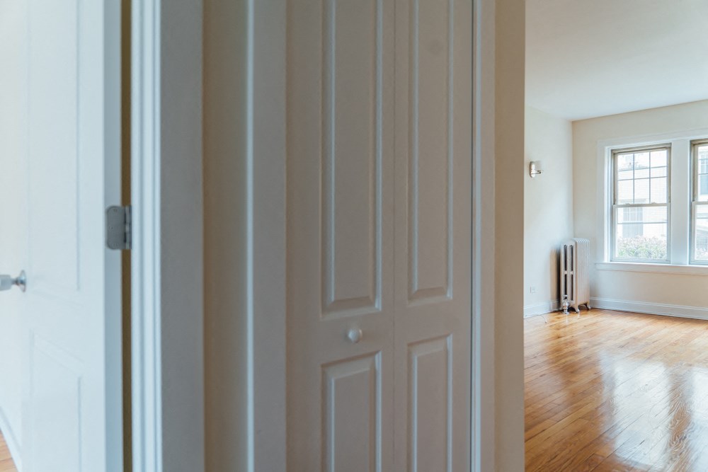 the door is open to a living room with a hard wood floor