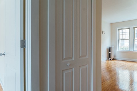the door is open to a living room with a hard wood floor