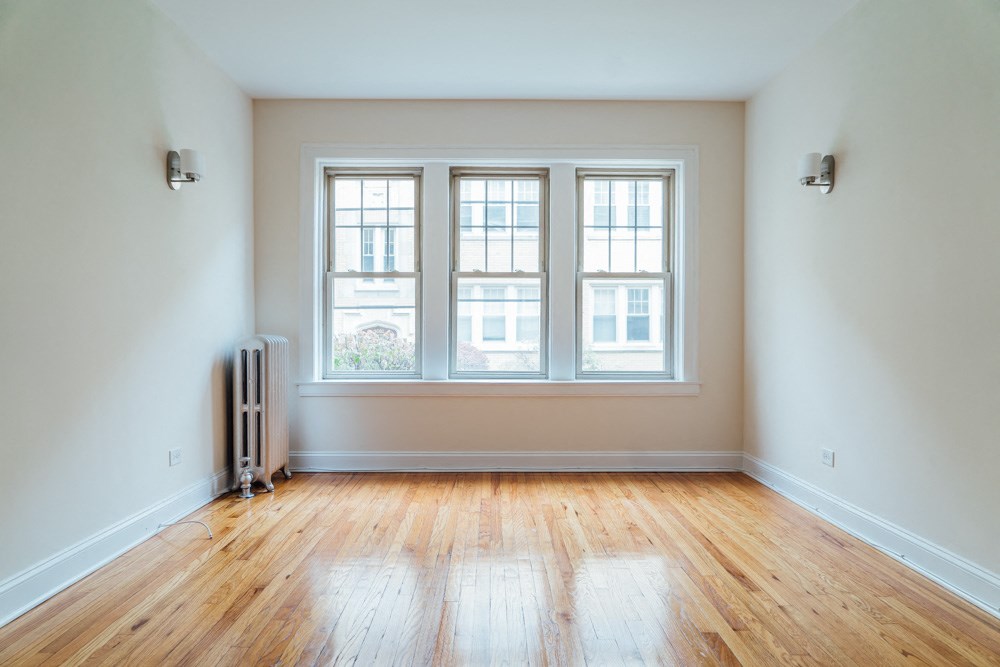 an empty room with three windows and a wooden floor