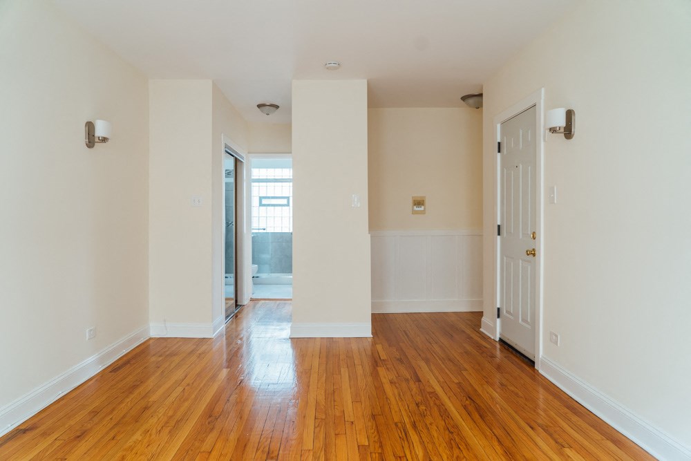 an empty living room with wood floors and white walls