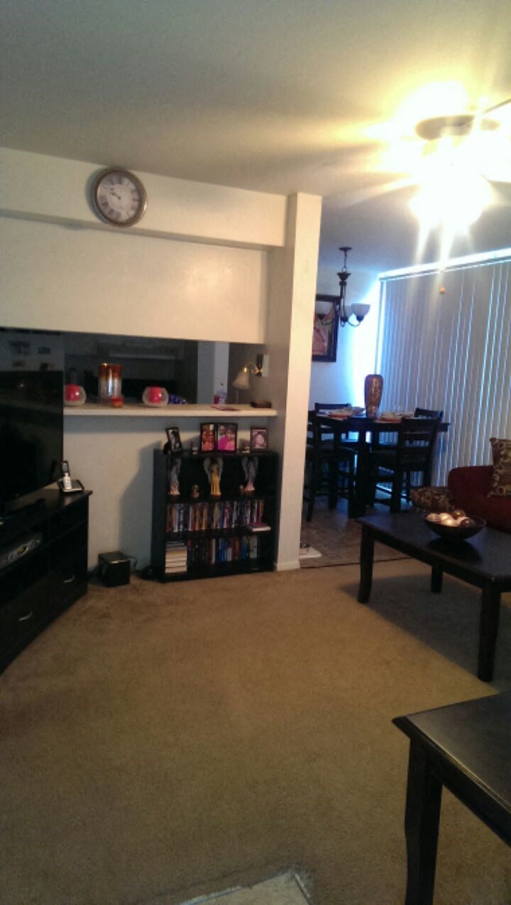 a living room and dining room with a clock on the wall