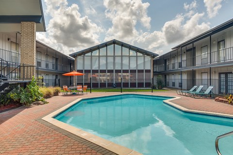 A swimming pool surrounded by a glass wall and a red umbrella.