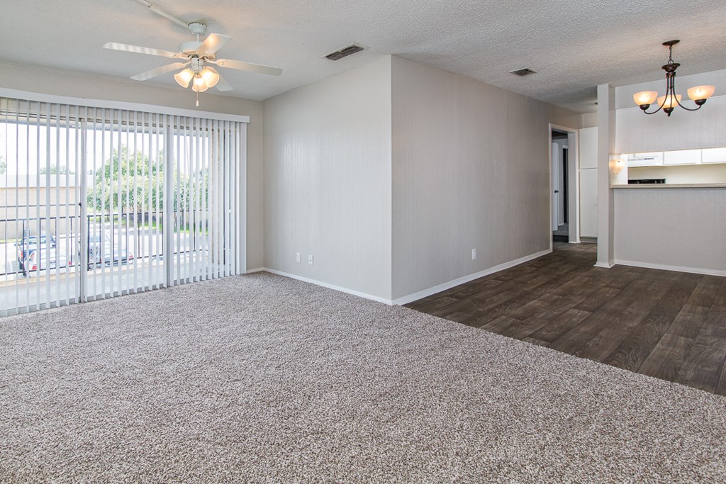 an empty living room with a ceiling fan and a window
