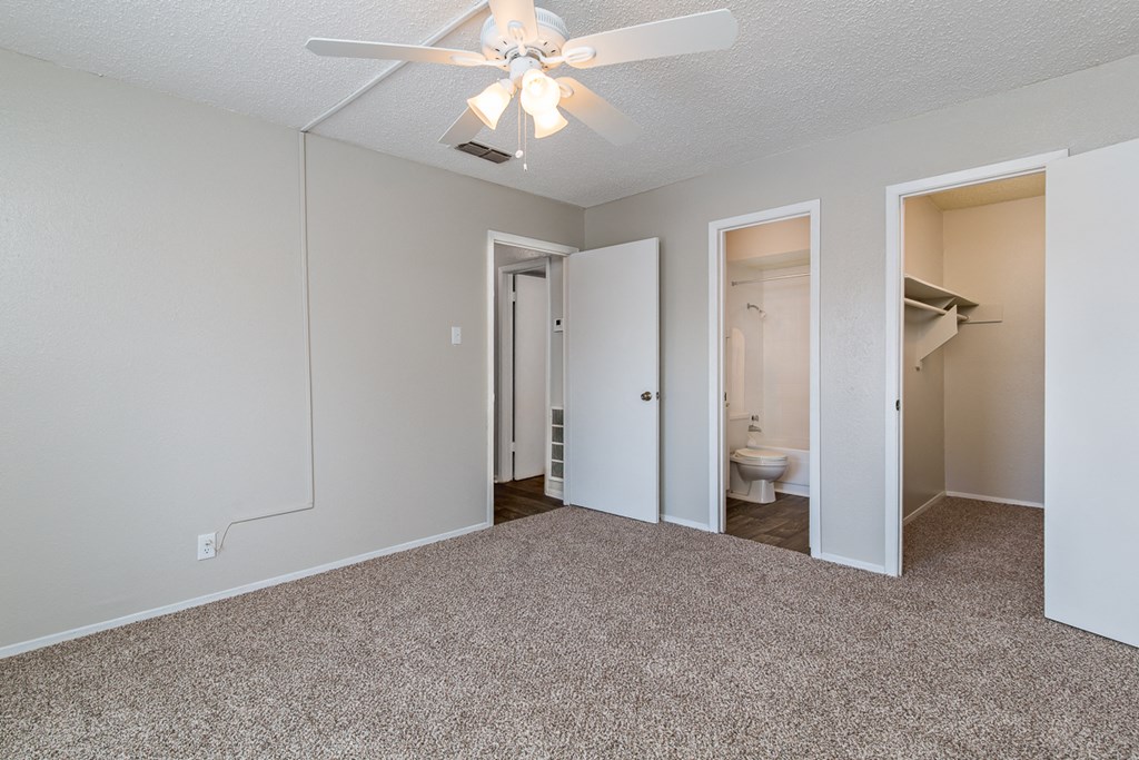 an empty bedroom with a ceiling fan and a closet