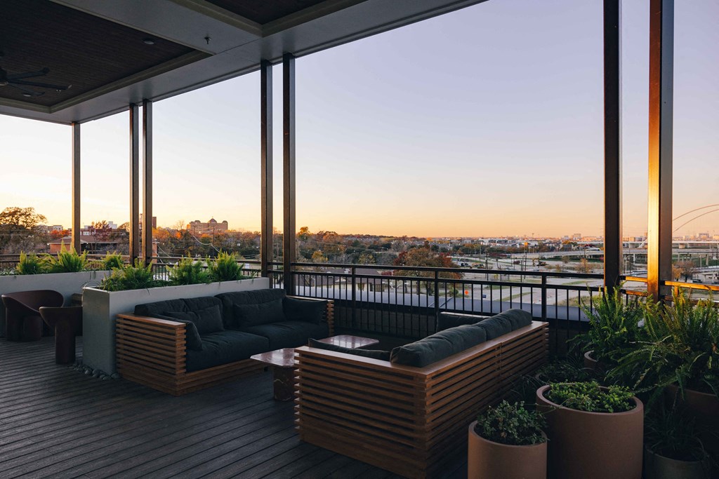 A wooden deck with a couch and potted plants.