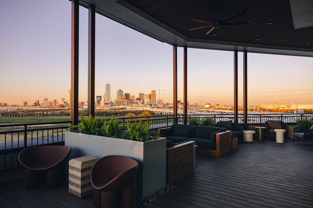 A balcony with a view of the city skyline at sunset.
