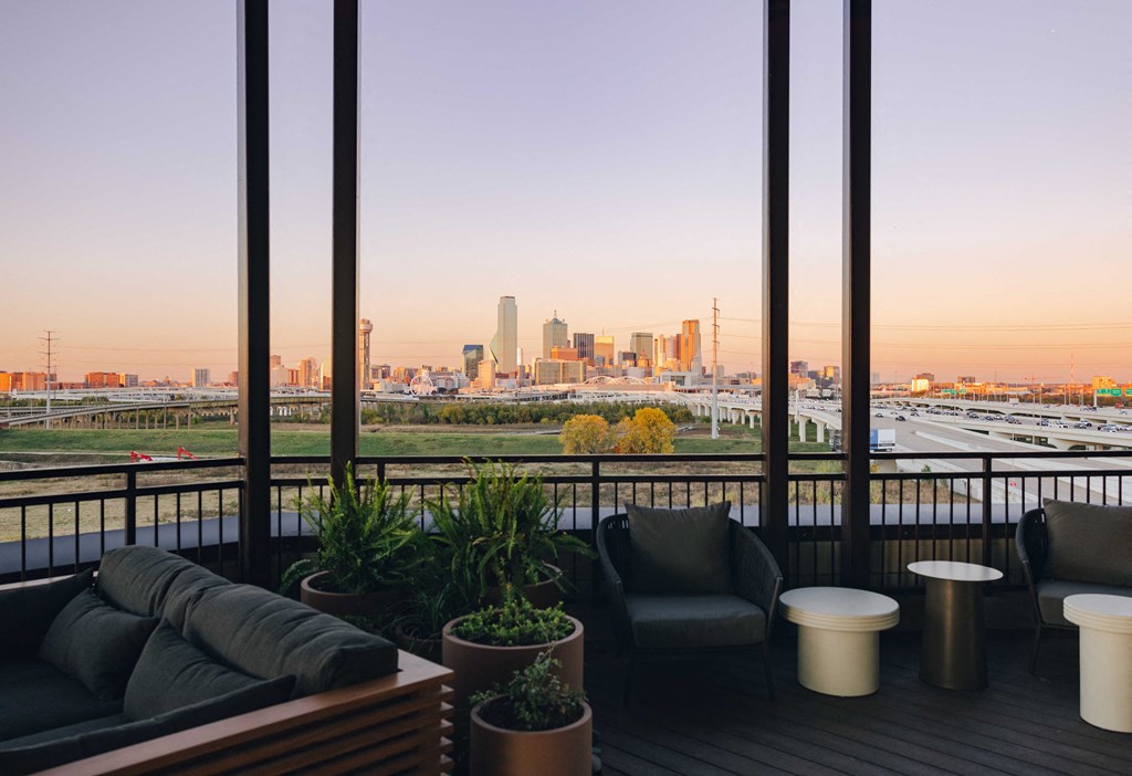 A balcony with a view of a city skyline at sunset.