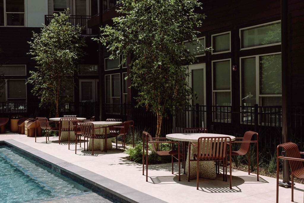 a poolside seating area with tables and chairs next to a pool