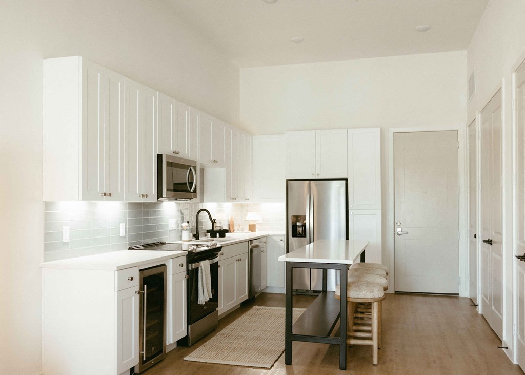 a white kitchen with a table and a refrigerator
