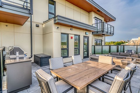 A modern outdoor dining area with a wooden table and chairs.