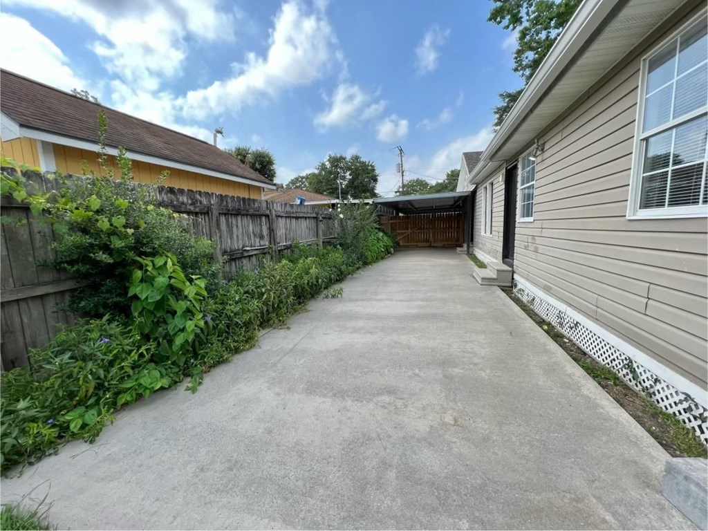 a long driveway next to a house with a fence