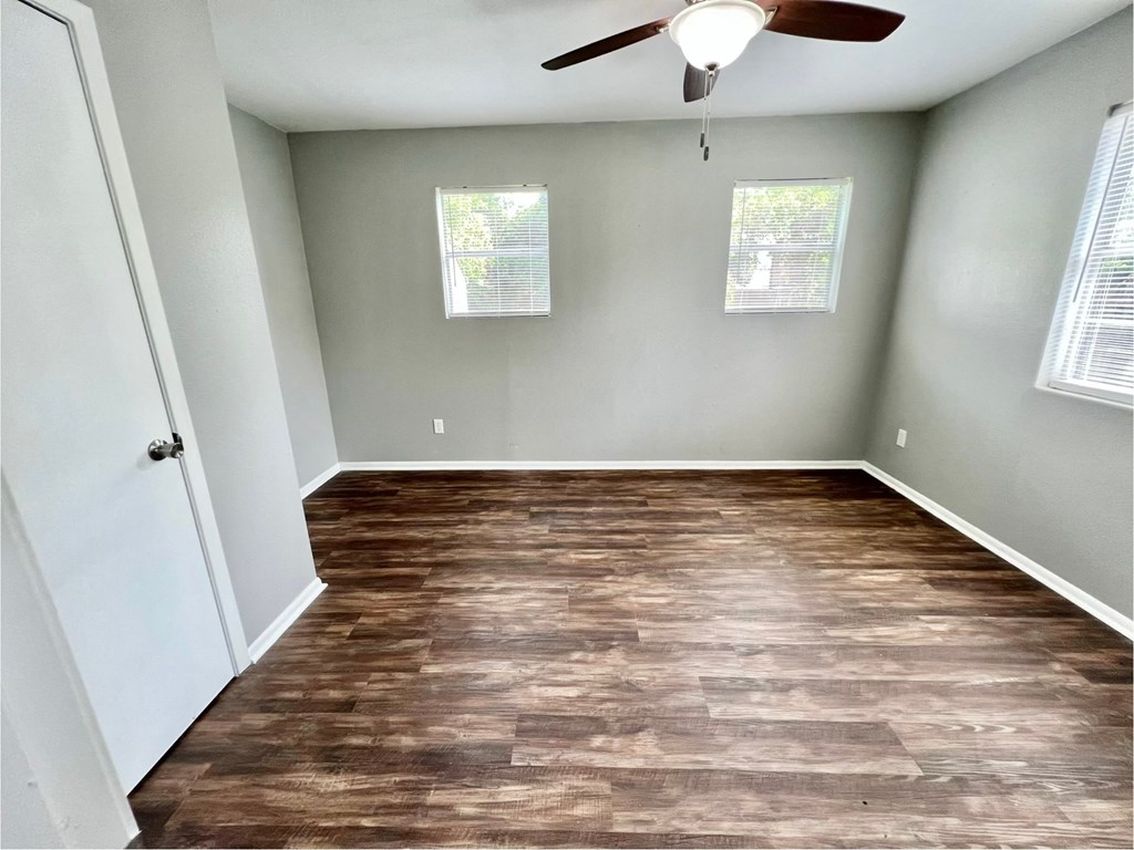 an empty room with wood floors and a ceiling fan