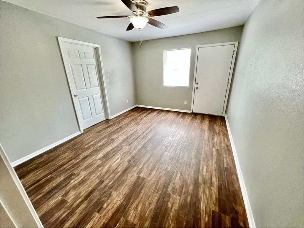 an empty living room with wood flooring and a ceiling fan