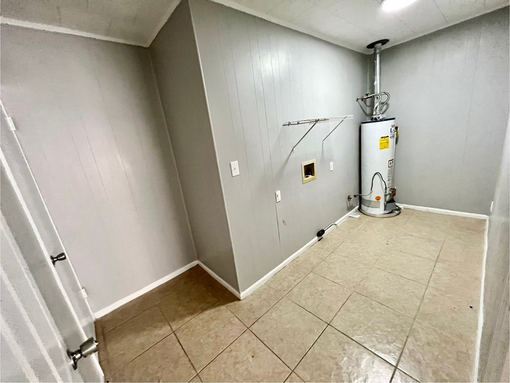 a room with a white wall and a water heater in the corner