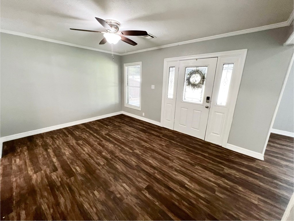 an empty living room with wood floors and a ceiling fan
