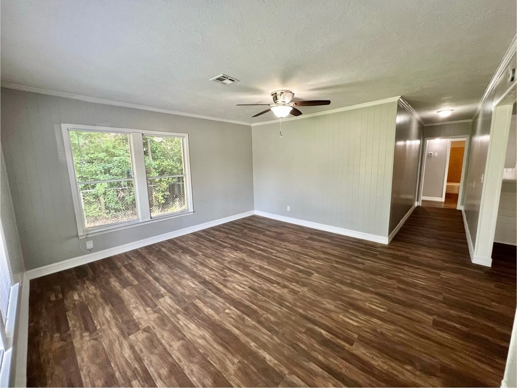 an empty living room with a ceiling fan and a window