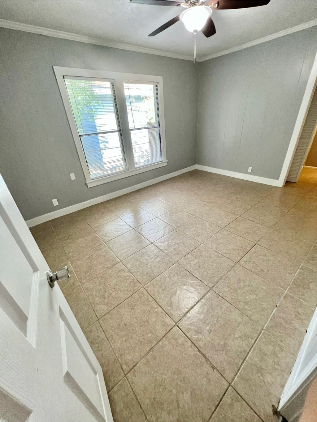 an empty living room with tiled floors and a window