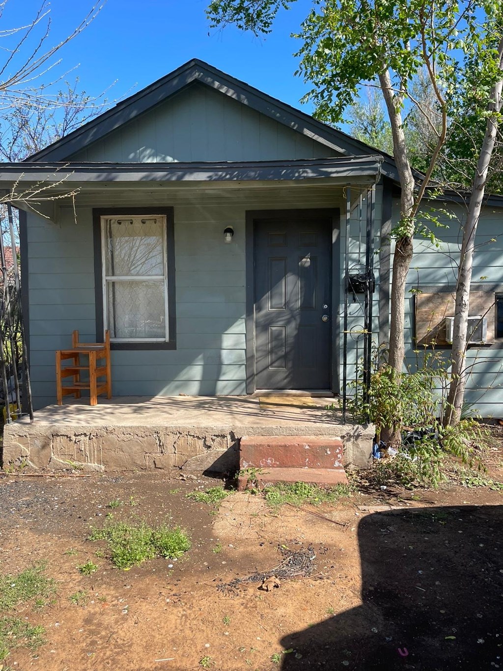 A small house with a grey siding and a white door.