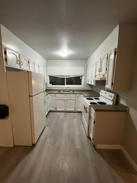 a kitchen with white cabinets and appliances and a window