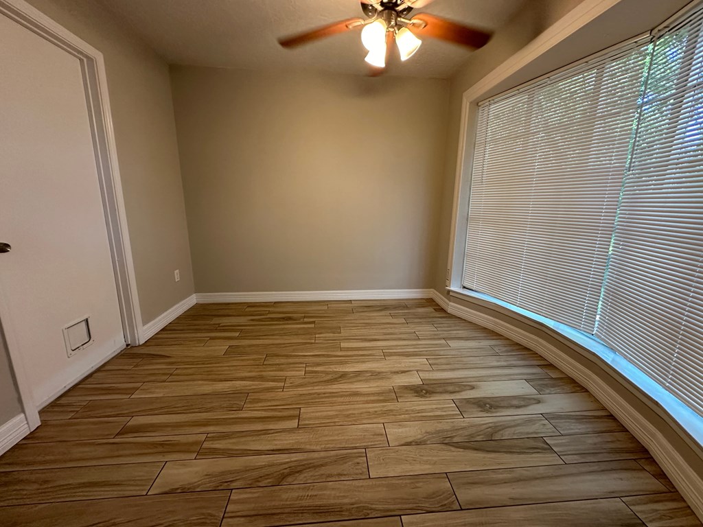 a living room with a large window and a ceiling fan