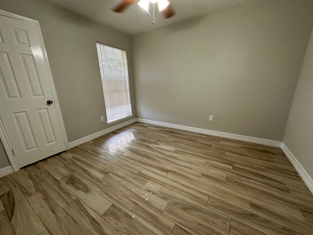 an empty living room with wooden floors and a white door