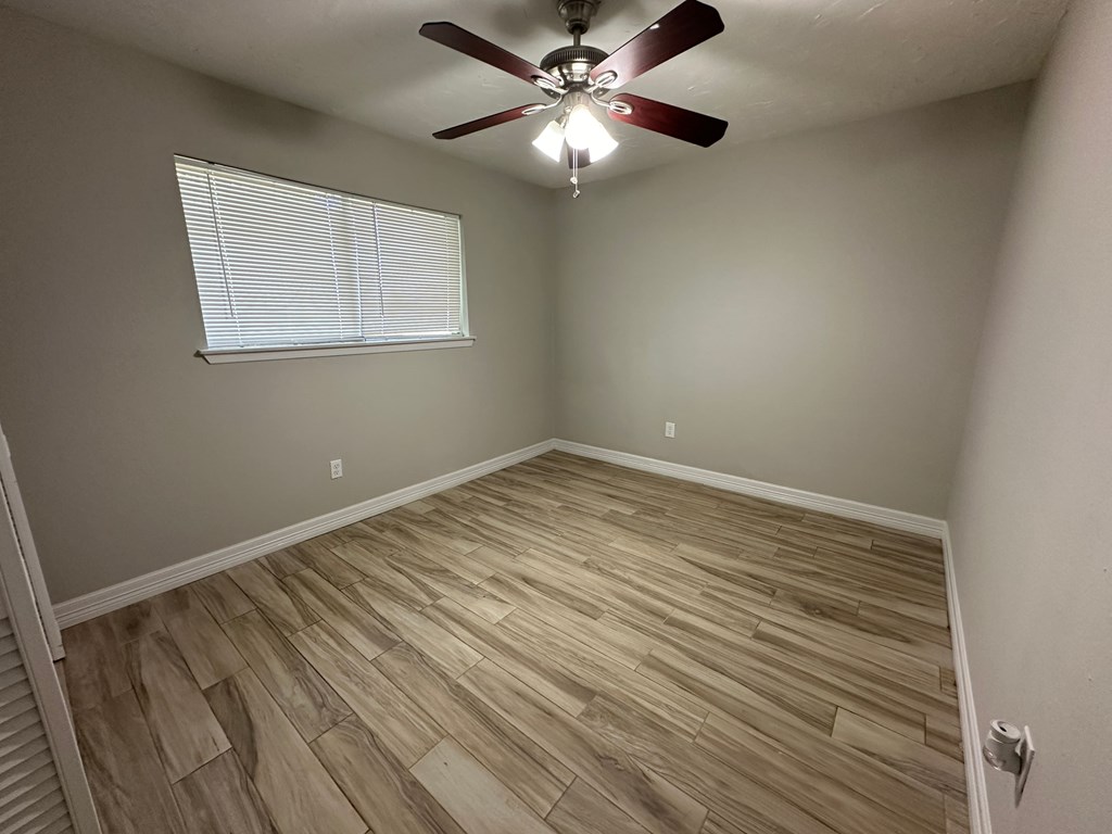 a bedroom with wood flooring and a ceiling fan