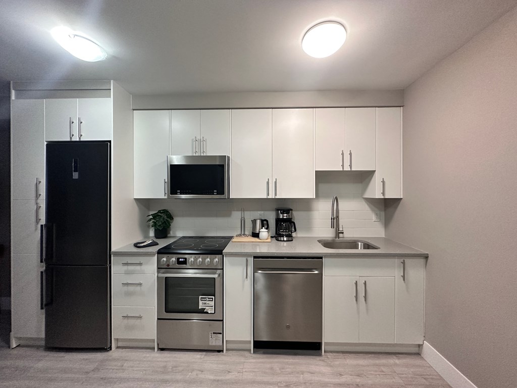 a kitchen with white cabinets and stainless steel appliances and a black refrigerator