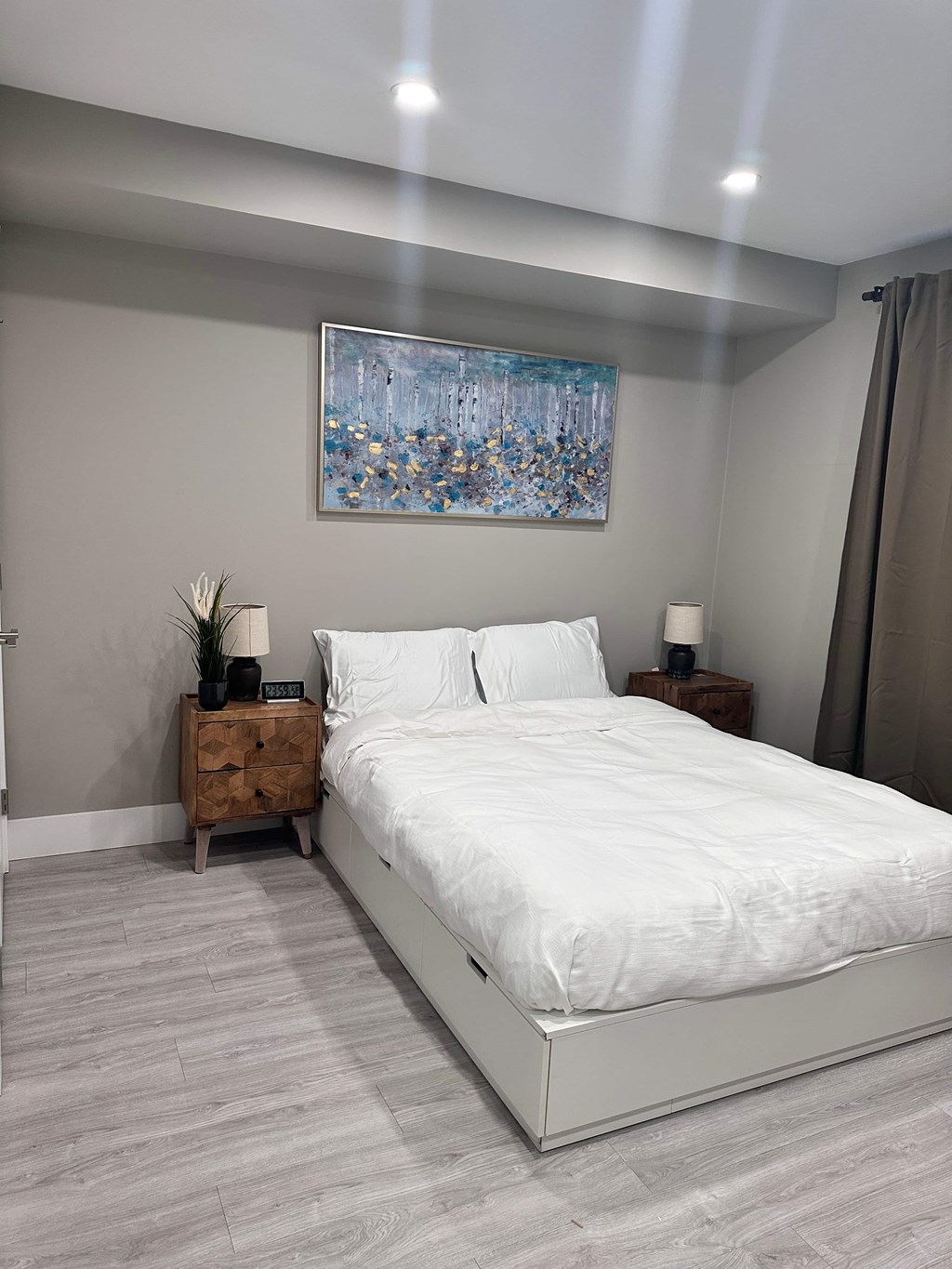 a bedroom with a white bed and a painting on the wall