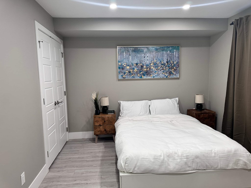 a bedroom with a white bed and a painting on the wall