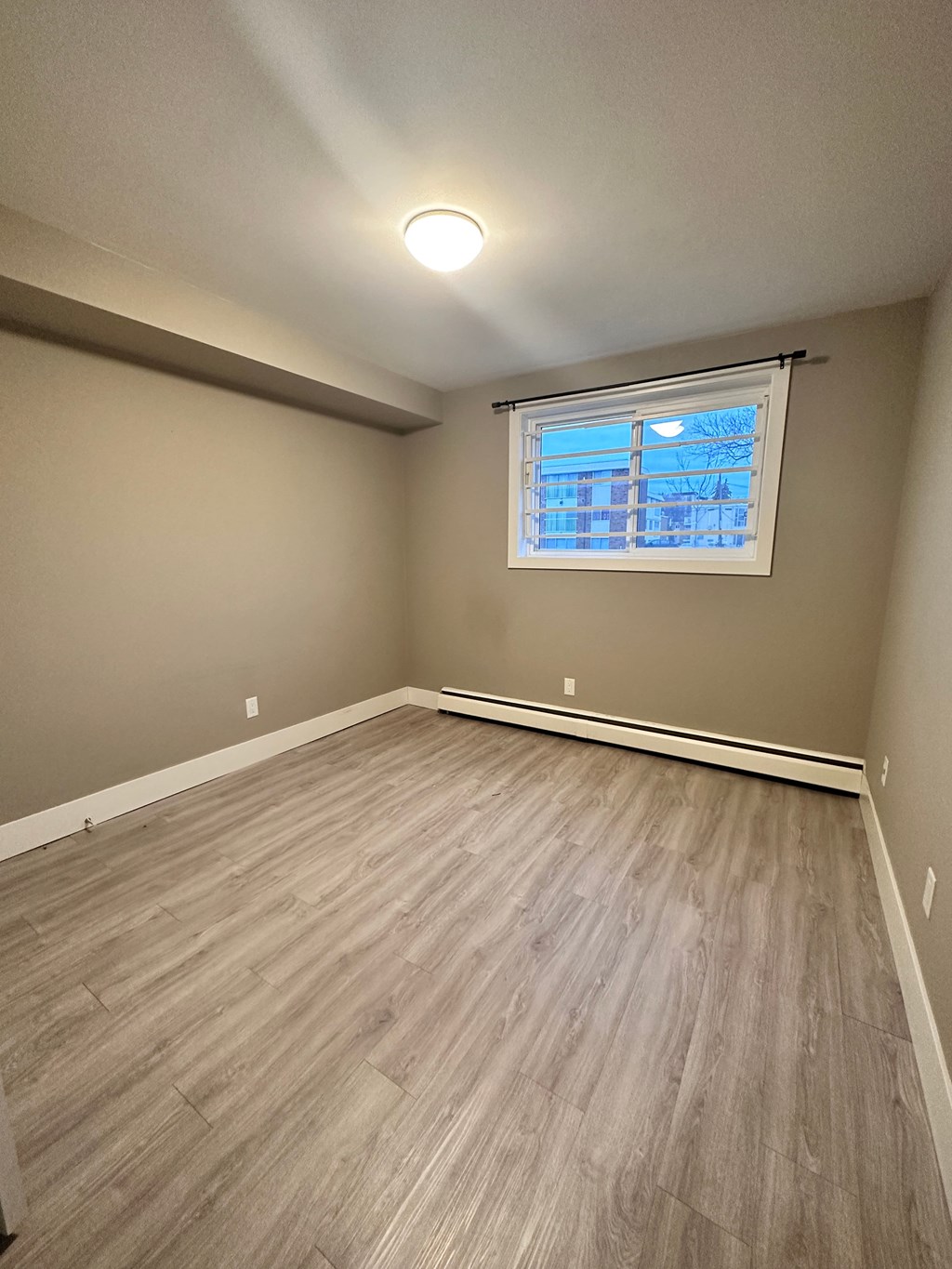 an empty living room with wood floors and a window