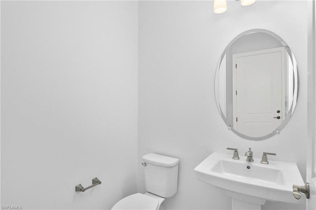 a white bathroom with a mirror and a toilet and a sink